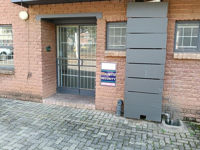 Exterior view of the industrial property entrance featuring a brick facade, security gate, and paved driveway area.