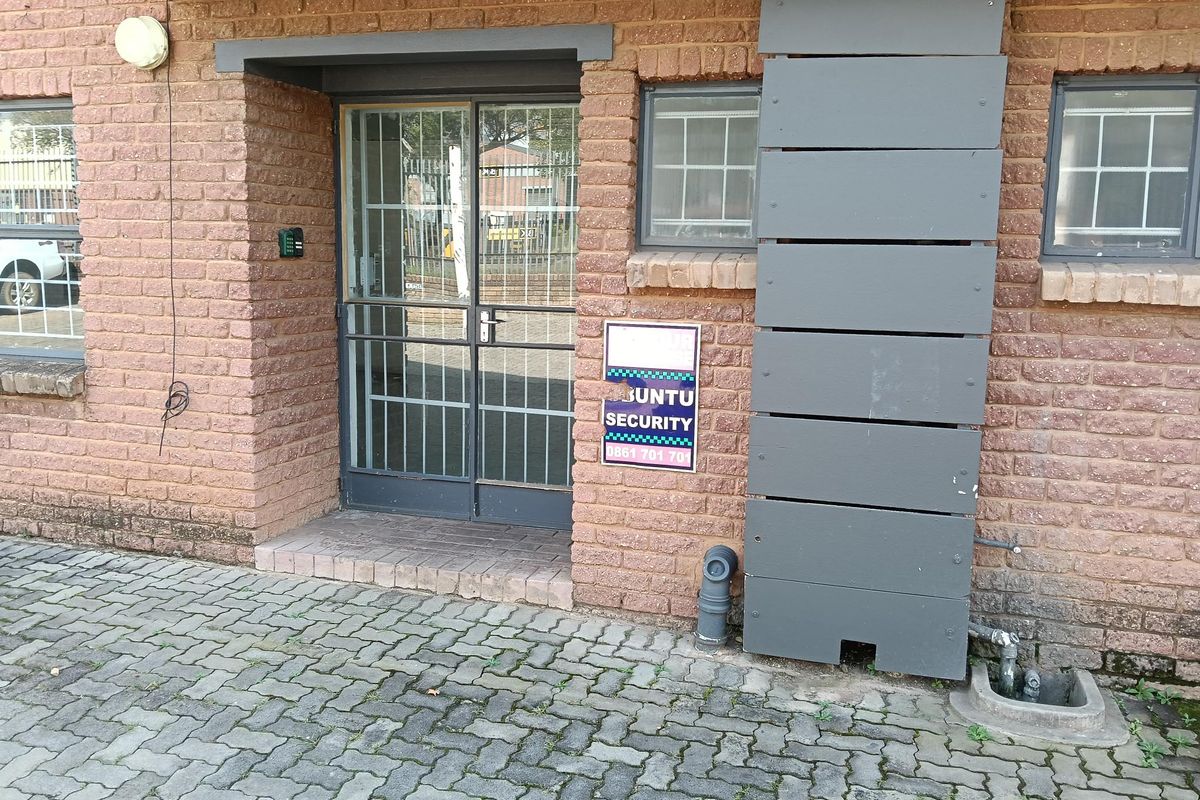 Exterior view of the industrial property entrance featuring a brick facade, security gate, and paved driveway area.