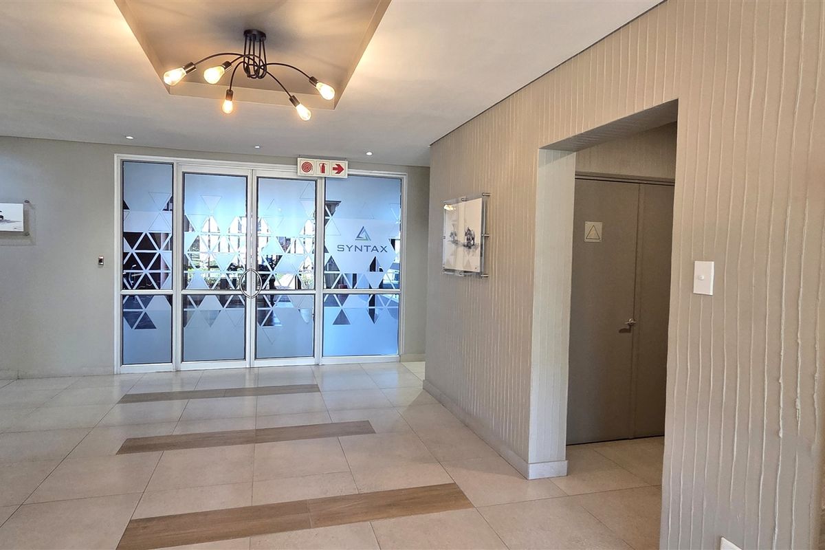 Modern office entrance lobby featuring tiled flooring, textured wall accents, recessed ceiling lighting, and glass-paneled double doors.