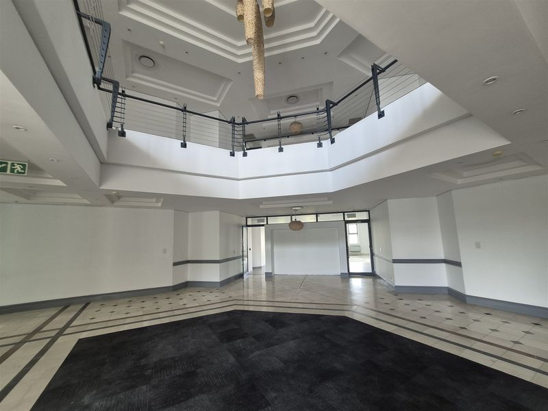 Spacious double-volume entrance foyer featuring a mezzanine level, recessed ceiling details, and elegant tiled flooring in a professional office building.