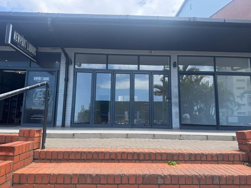Front facade of a retail storefront featuring large glass folding doors, brick steps, and a covered entrance area.