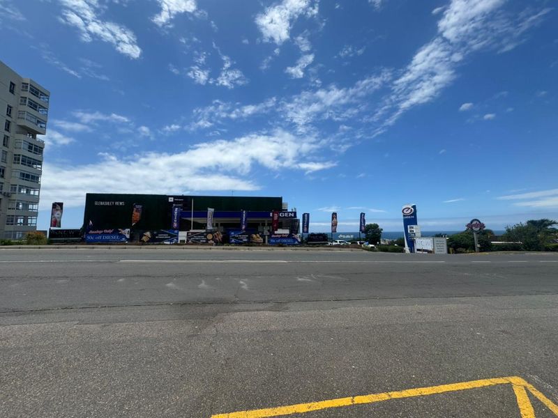 Street view of a retail fuel station and convenience store facility with prominent branding and signage, situated along a main road.