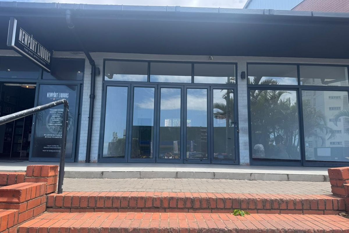 Front facade of a retail storefront featuring large glass folding doors, brick steps, and a covered entrance area.