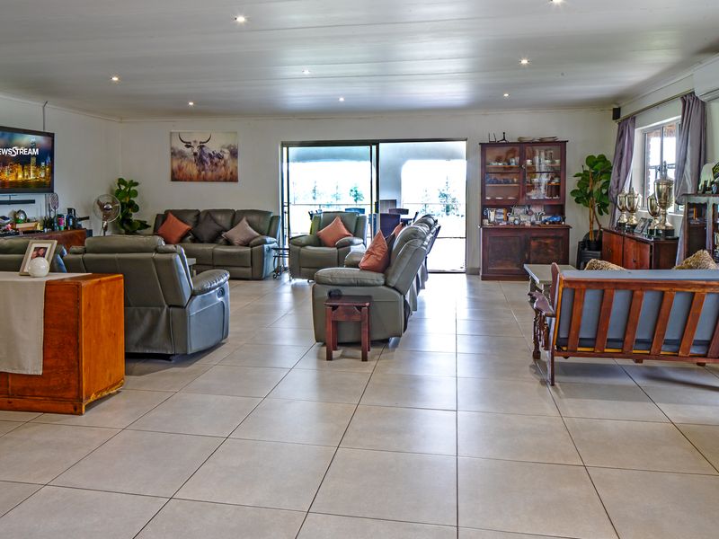 Spacious open-plan living area featuring large format floor tiles, recessed lighting, and sliding glass doors leading to an outdoor patio space.