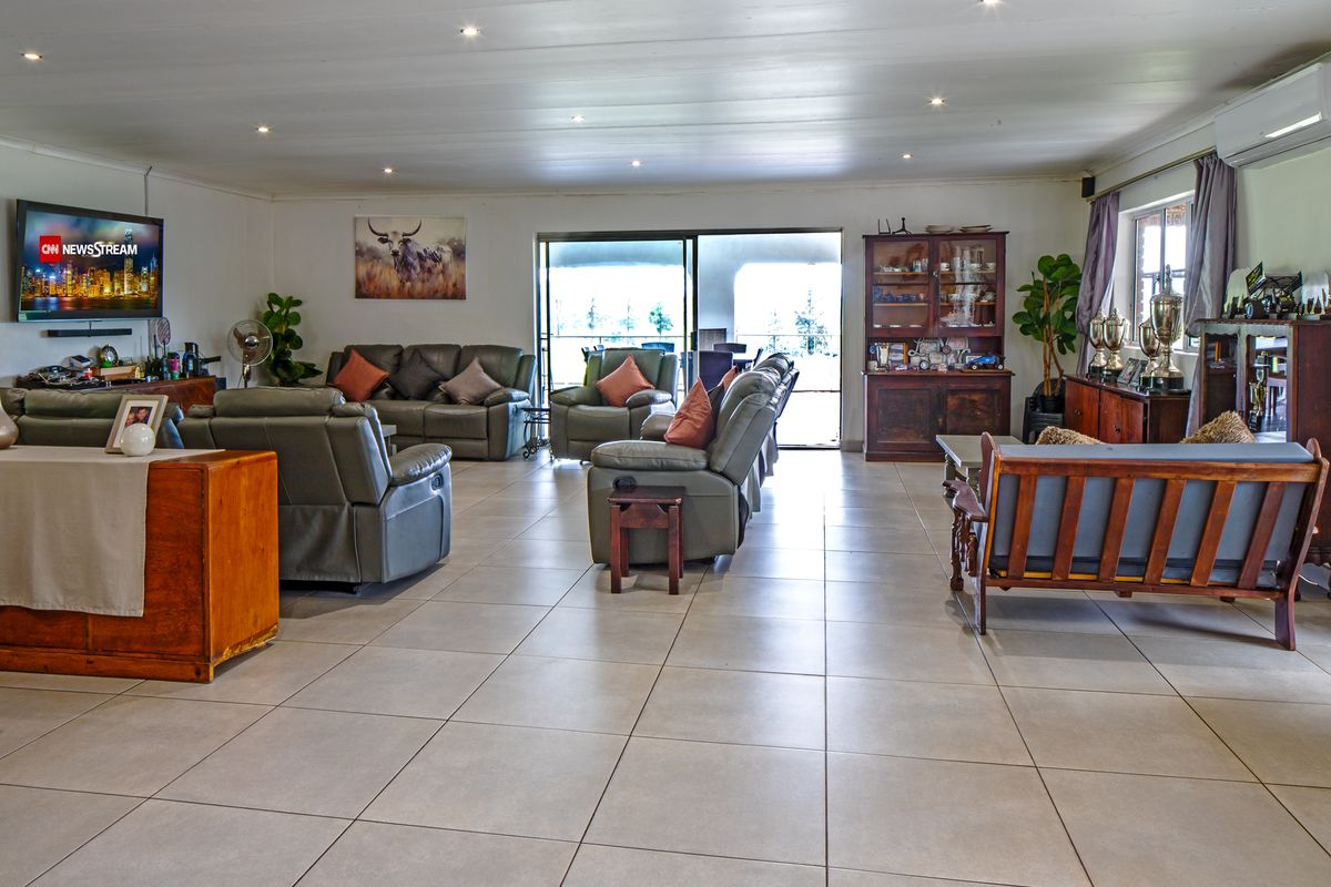 Spacious open-plan living area featuring large format floor tiles, recessed lighting, and sliding glass doors leading to an outdoor patio space.