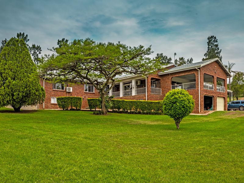 Rear view of a brick farmhouse featuring a spacious covered patio, established garden, and integrated garage.