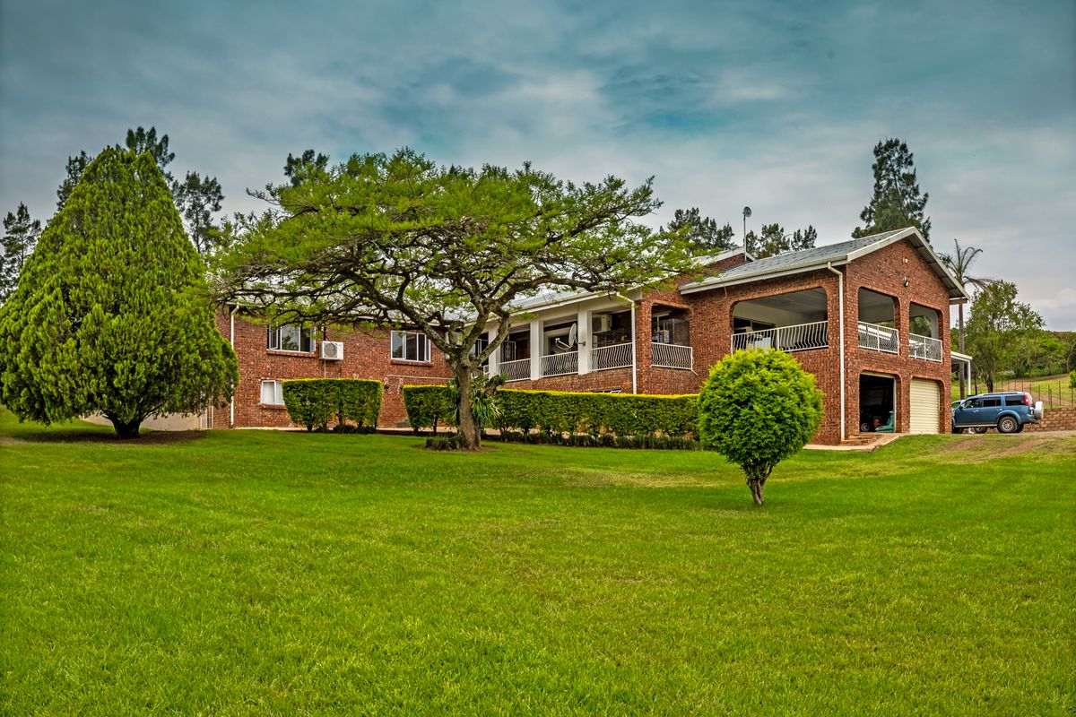Rear view of a brick farmhouse featuring a spacious covered patio, established garden, and integrated garage.