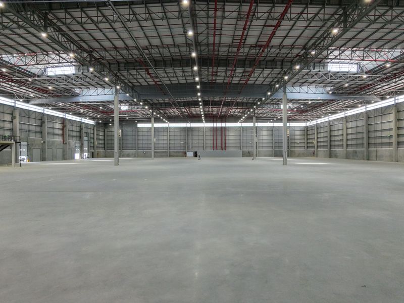 Expansive industrial warehouse space featuring high ceilings, concrete flooring, integrated fire safety systems, and a mezzanine level.