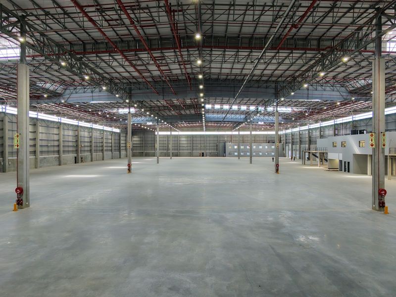 Expansive industrial warehouse space featuring high ceilings, concrete flooring, integrated fire safety systems, and a mezzanine level for versatile operational use.