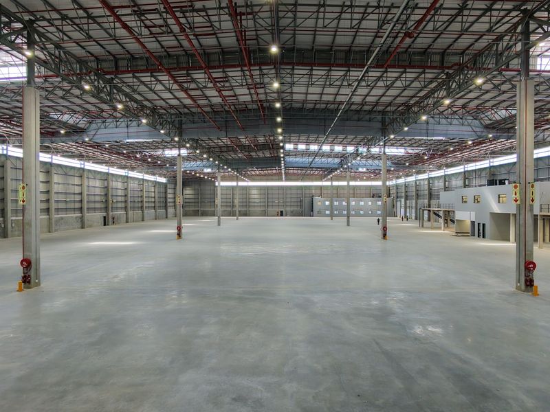 Expansive industrial warehouse space featuring high ceilings, concrete flooring, integrated fire sprinkler systems, and a mezzanine level for versatile operational use.