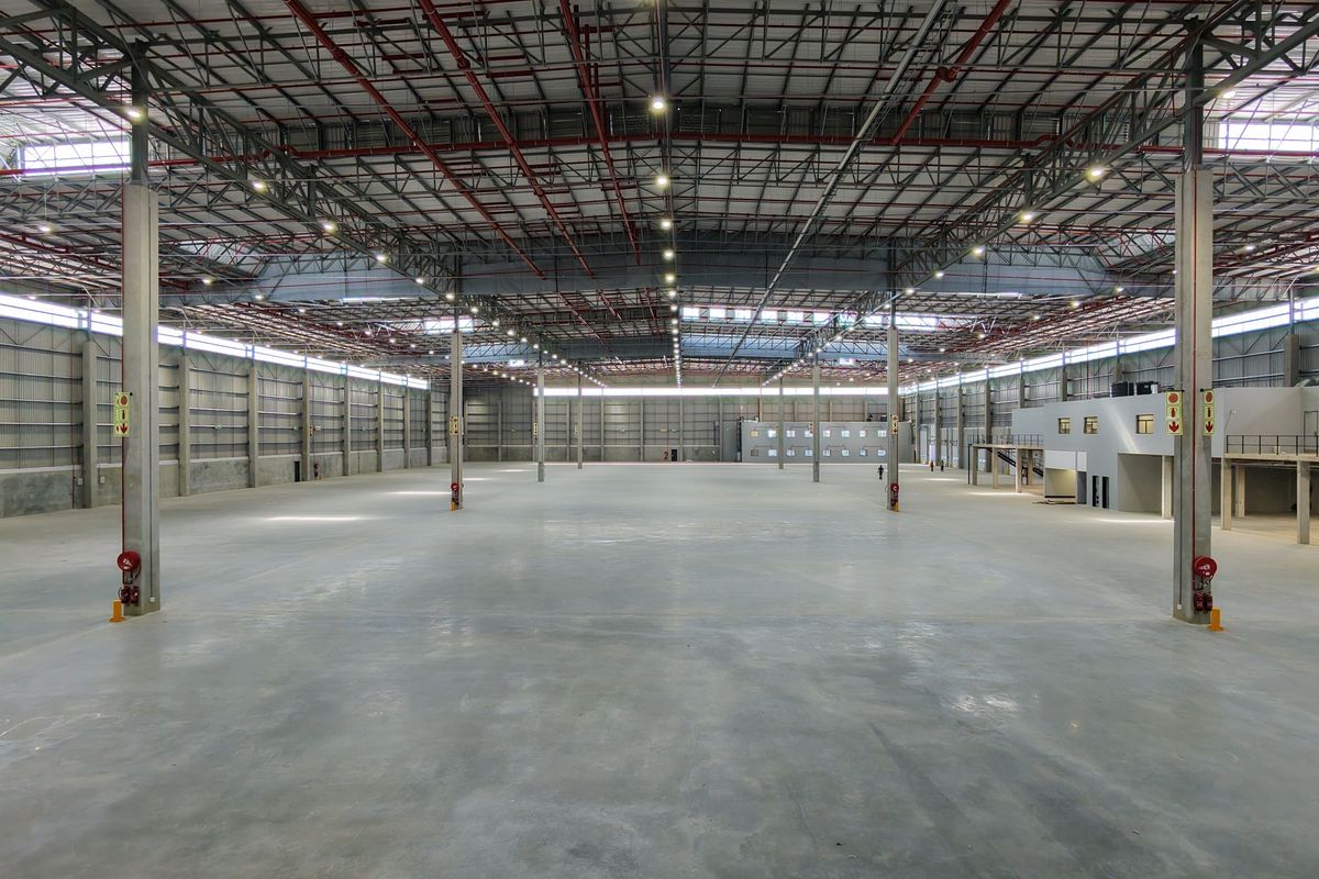 Expansive industrial warehouse space featuring high ceilings, concrete flooring, integrated fire sprinkler systems, and a mezzanine level for versatile operational use.