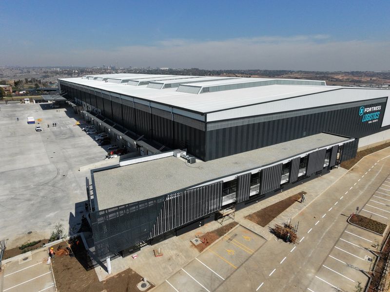 Aerial view of a modern industrial logistics facility featuring a large warehouse structure, extensive concrete loading yard, and dedicated parking areas.