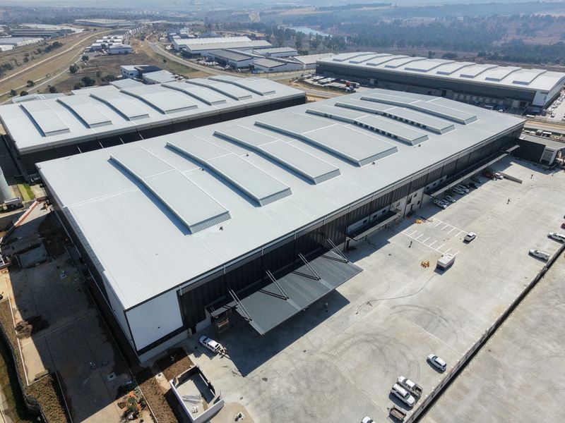 Aerial view of a large industrial warehouse facility featuring extensive concrete yard space, metal roofing, and loading canopy infrastructure.