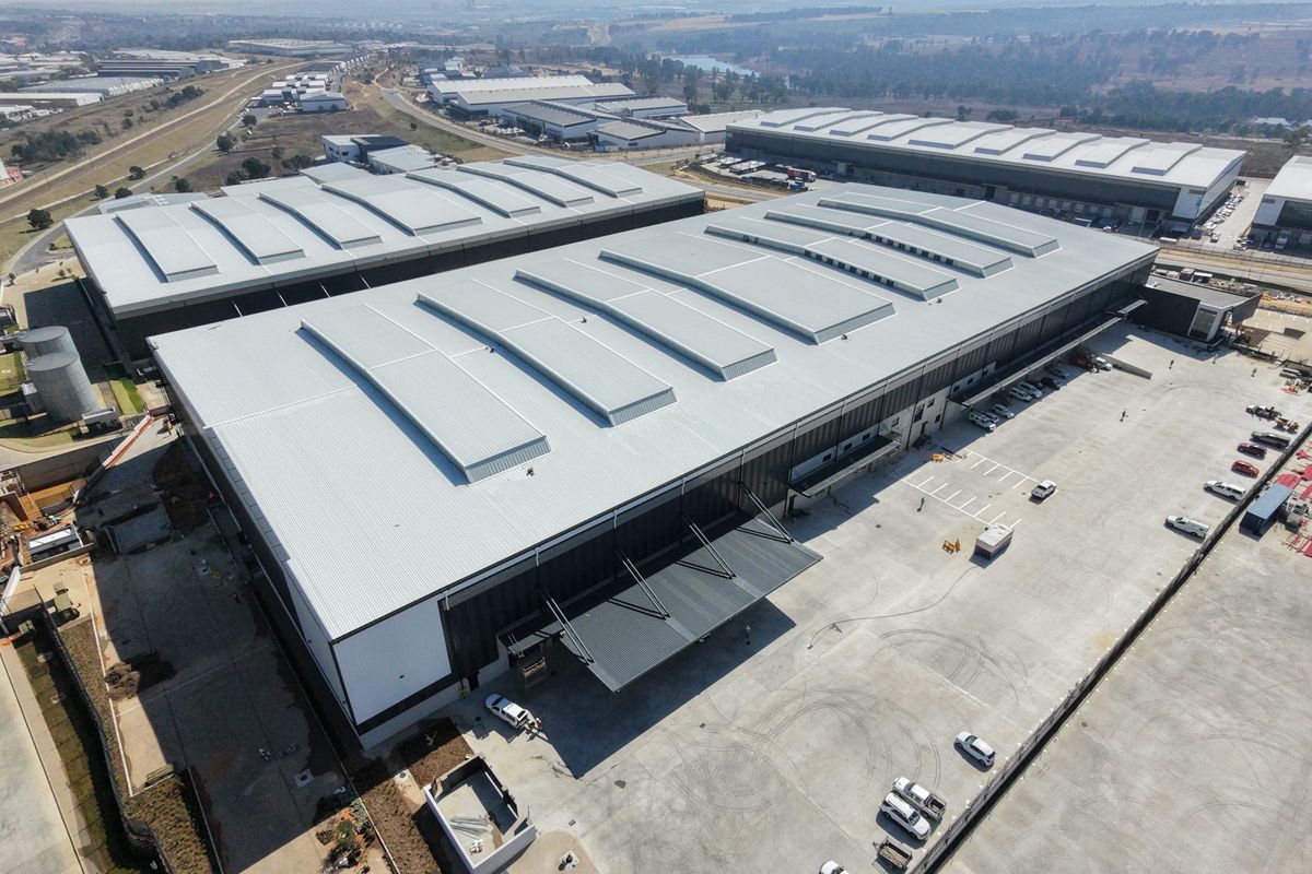 Aerial view of a large industrial warehouse facility featuring extensive concrete yard space, metal roofing, and loading canopy infrastructure.