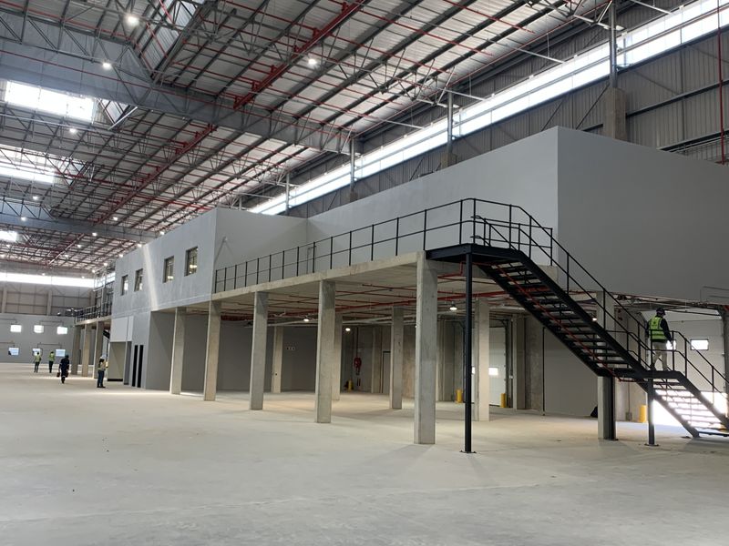 Spacious industrial warehouse interior featuring a mezzanine level with steel staircase access, high ceilings, and integrated fire sprinkler infrastructure.