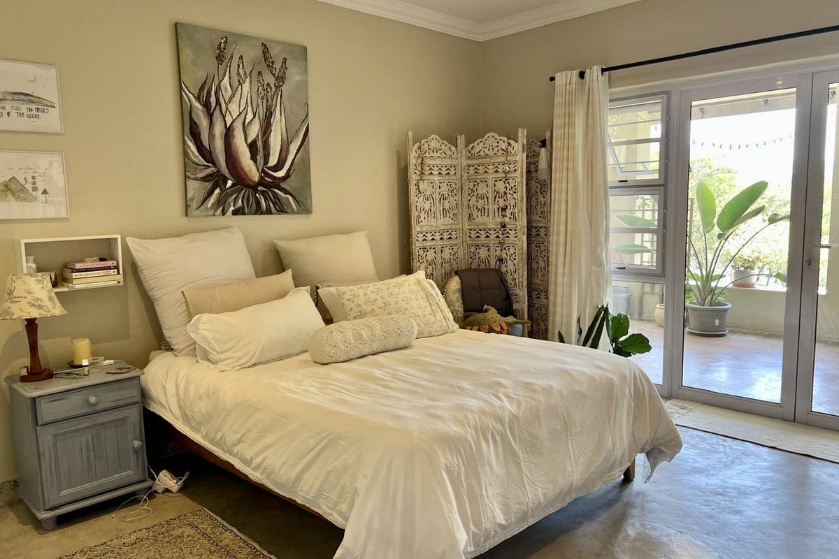 A bright bedroom featuring polished concrete floors and large aluminium sliding doors providing direct access to an outdoor patio area.