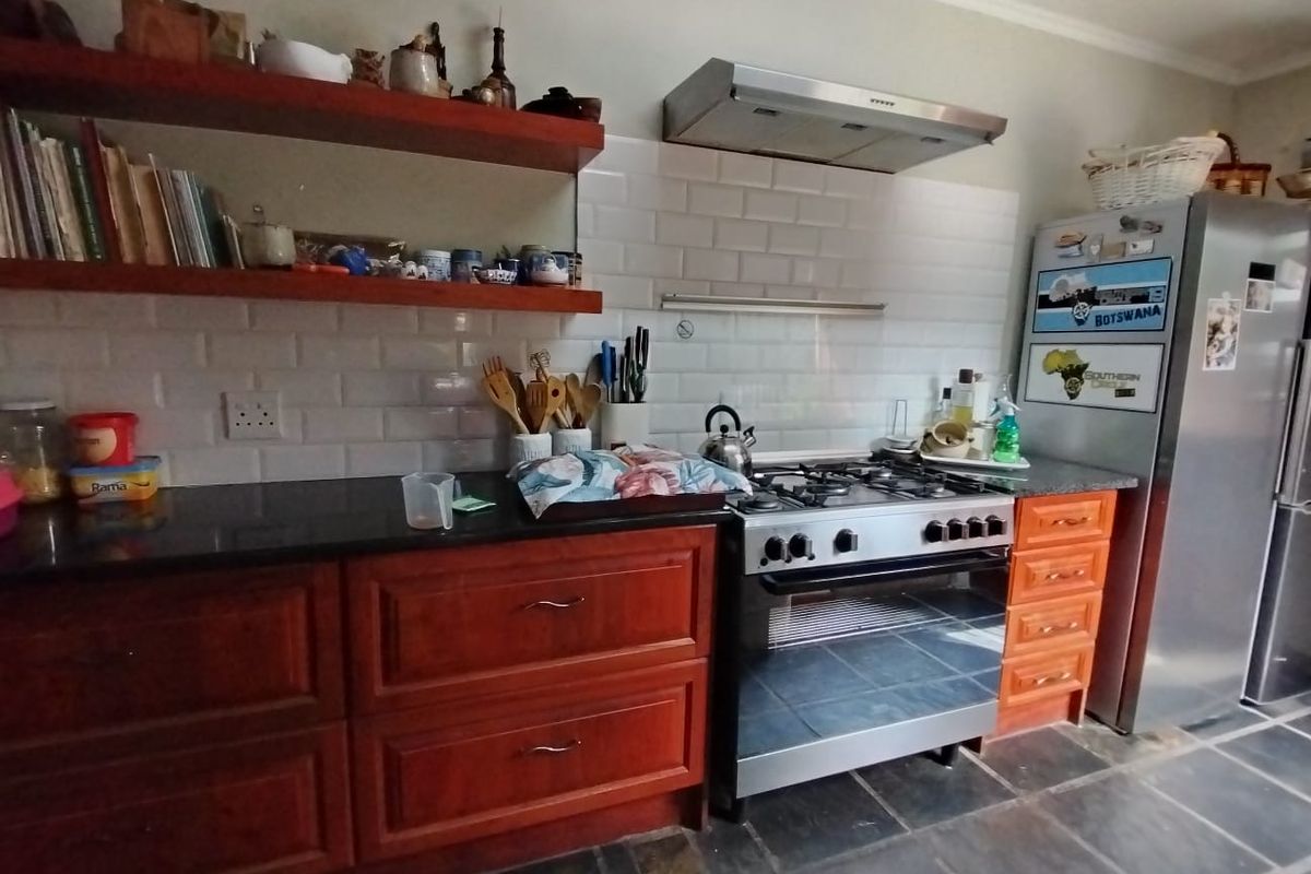 A functional kitchen featuring wooden cabinetry, granite countertops, a gas stove with an extractor fan, and classic subway tile backsplash.