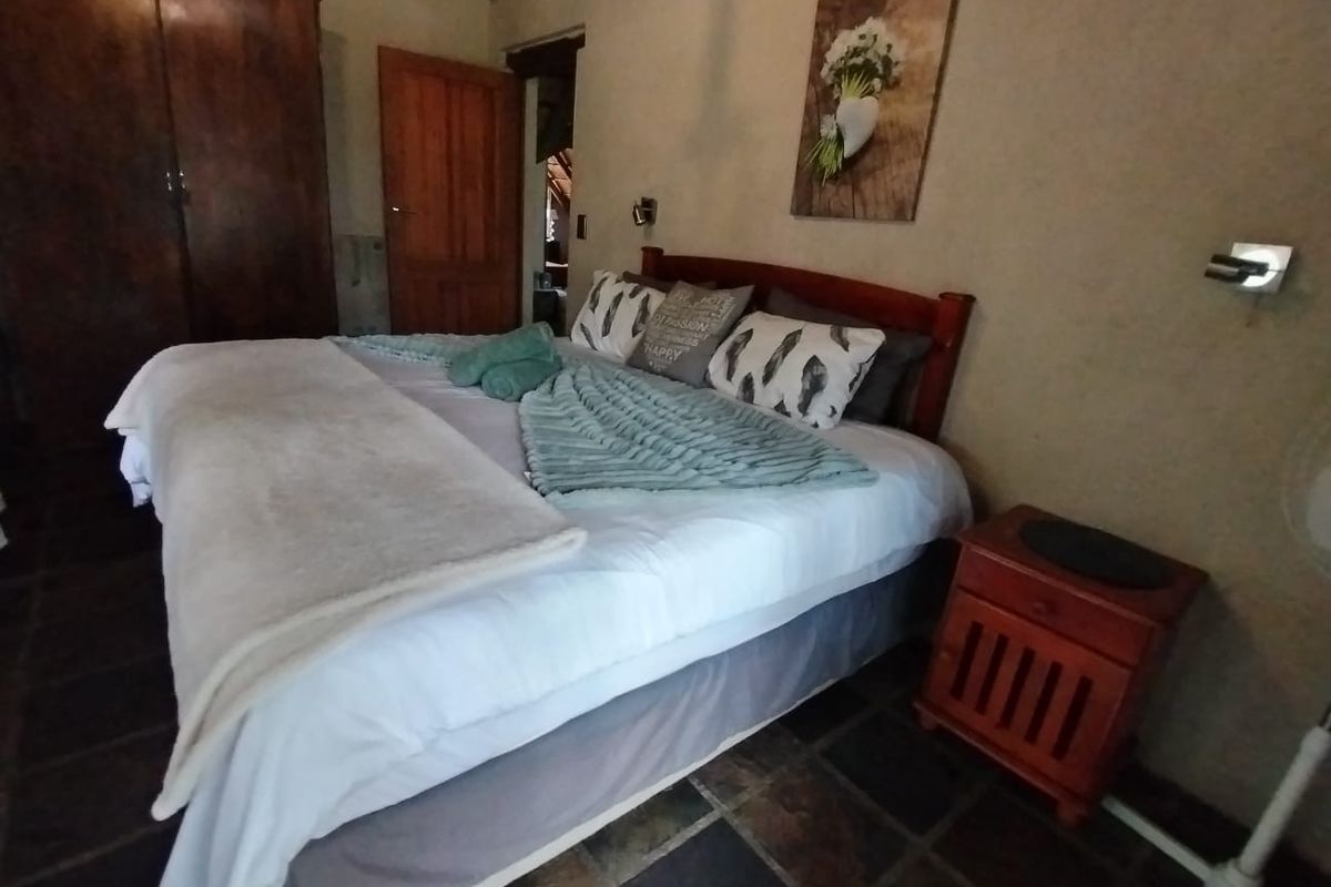 A rustic bedroom featuring stone tile flooring, wooden door, and wall-mounted lighting, offering a cozy and traditional farm-style atmosphere.