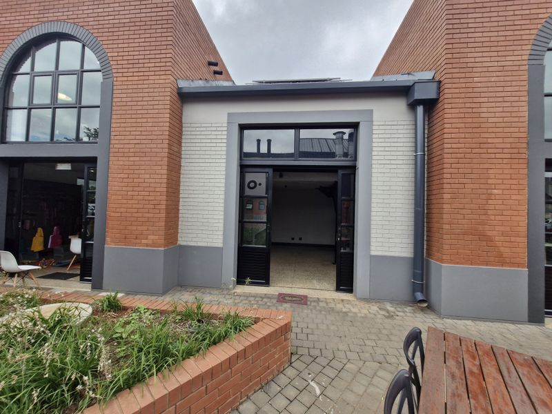Exterior view of a retail property featuring a brick facade, arched windows, and a paved courtyard entrance.