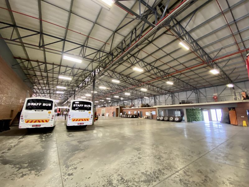 Spacious industrial warehouse facility featuring high-clearance steel roof trusses, polished concrete flooring, and an integrated mezzanine level suitable for storage or office use.