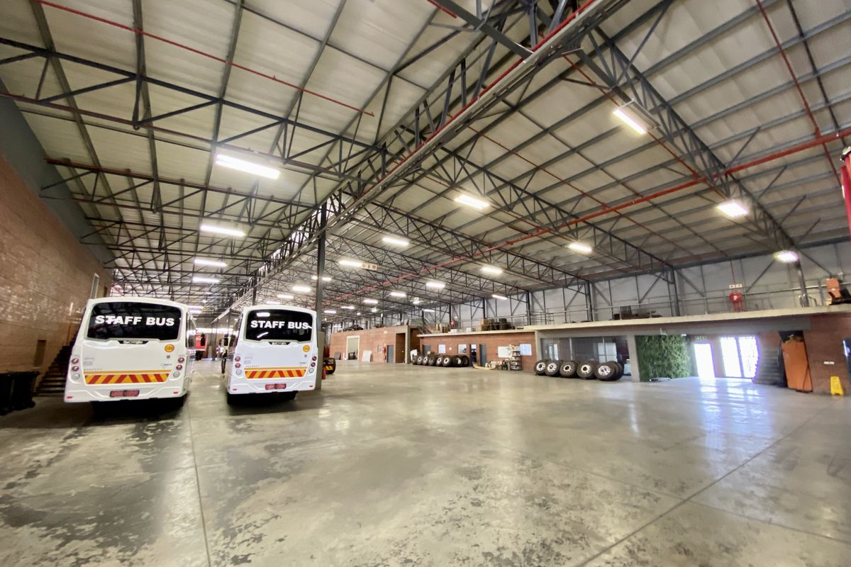 Spacious industrial warehouse facility featuring high-clearance steel roof trusses, polished concrete flooring, and an integrated mezzanine level suitable for storage or office use.