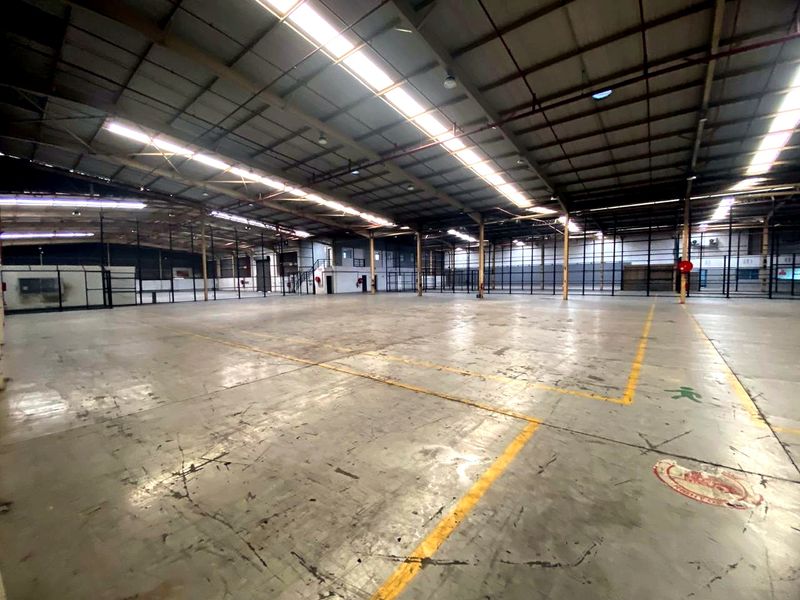 Expansive industrial warehouse space featuring high ceilings, concrete flooring, integrated skylights, and robust steel structural framing, suitable for various commercial or storage operations.
