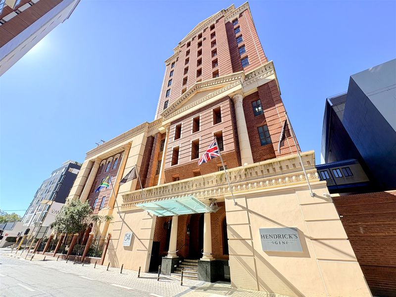 A professional exterior view of a multi-story office building featuring a prominent glass entrance canopy, brick and stone facade, and street-level access.
