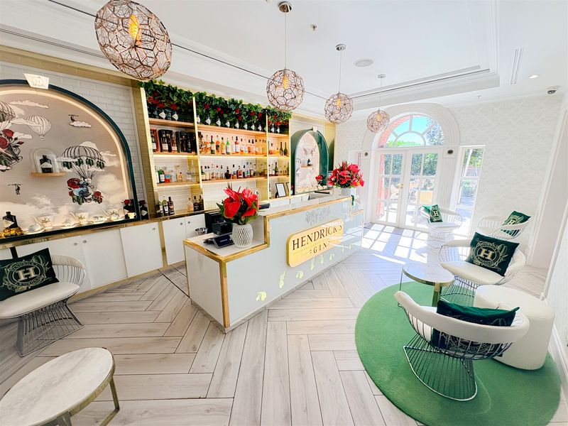 A professionally designed, high-end bar area featuring custom built-in cabinetry, elegant arched display niches, herringbone flooring, and bright natural light through arched french doors.