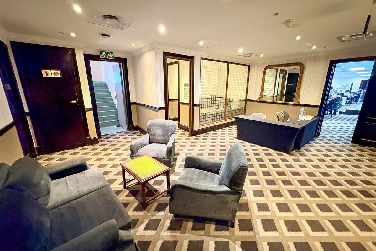 A professional office reception or waiting area featuring patterned carpeting, recessed lighting, and a glass partition wall.
