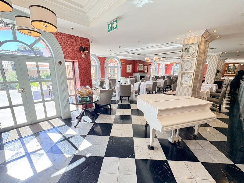 Spacious open-plan dining area featuring elegant checkered marble flooring, arched glass doors providing natural light, and sophisticated interior finishes.
