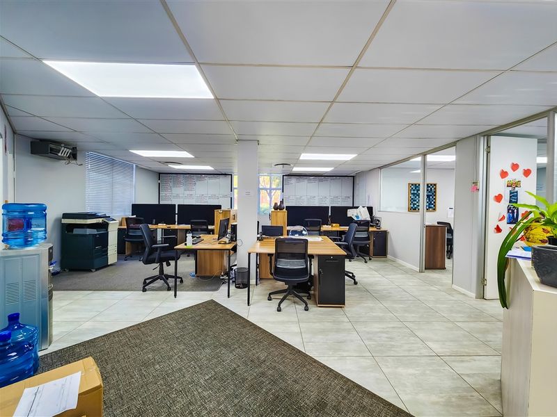 Open-plan office space featuring tiled flooring, suspended ceiling with recessed lighting, and glass partition walls for a professional work environment.