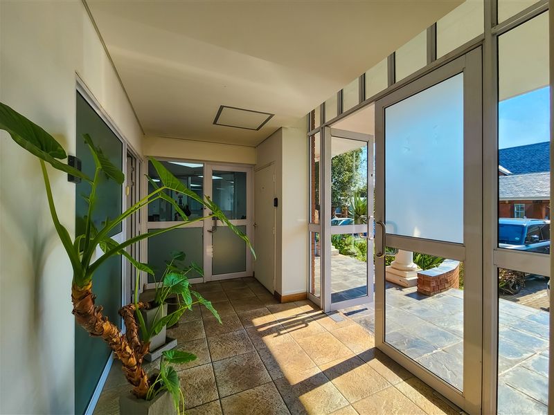 Bright and welcoming office entrance area featuring tiled flooring and large aluminium-framed glass doors providing natural light and exterior access.