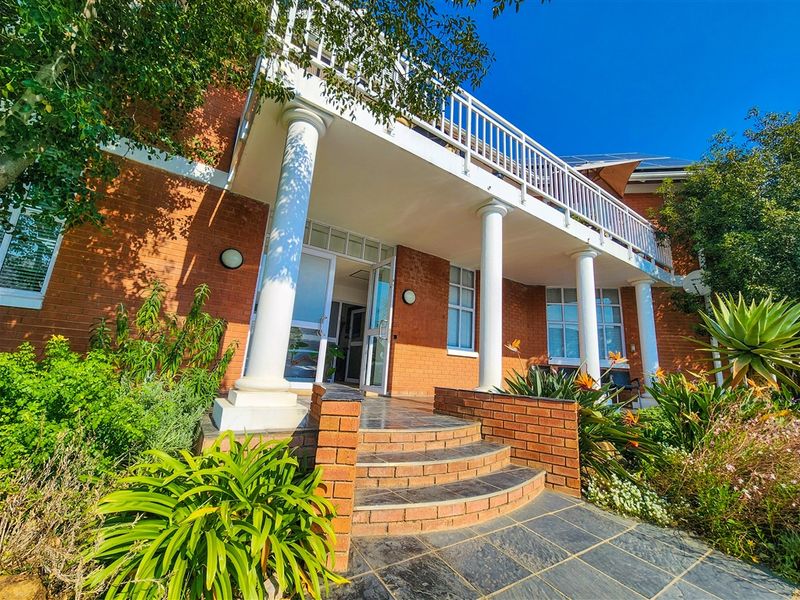 Front exterior view of a brick office building featuring a covered porch, balcony with white railings, and a tiled entrance staircase.