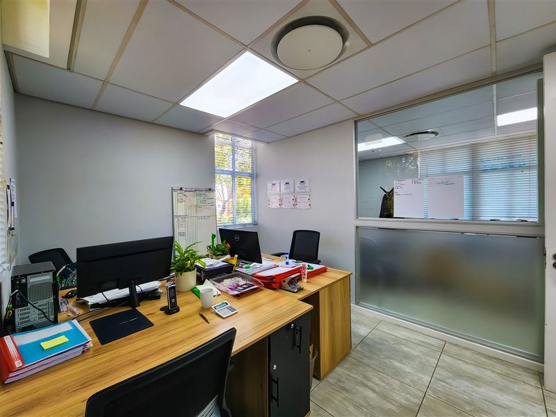 A functional office space featuring a suspended ceiling, recessed lighting, tiled flooring, and a glass partition wall for a professional work environment.
