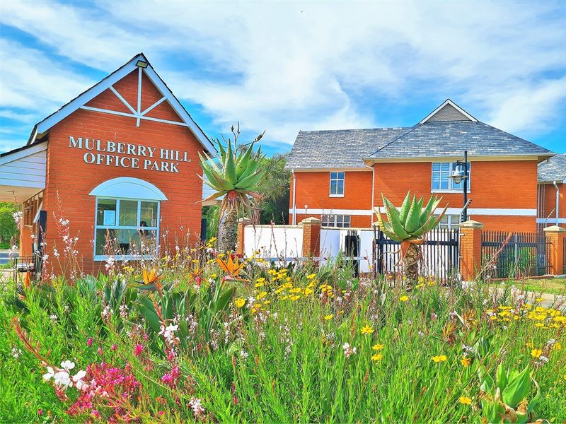 Front exterior view of Mulberry Hill Office Park featuring red brick buildings, gabled roof architecture, and well-maintained landscaped gardens.