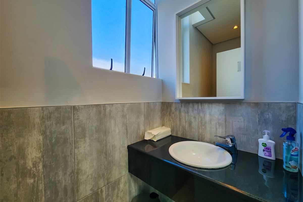 A clean and modern office bathroom featuring a granite vanity countertop, integrated basin, chrome mixer tap, and a wall-mounted mirror.