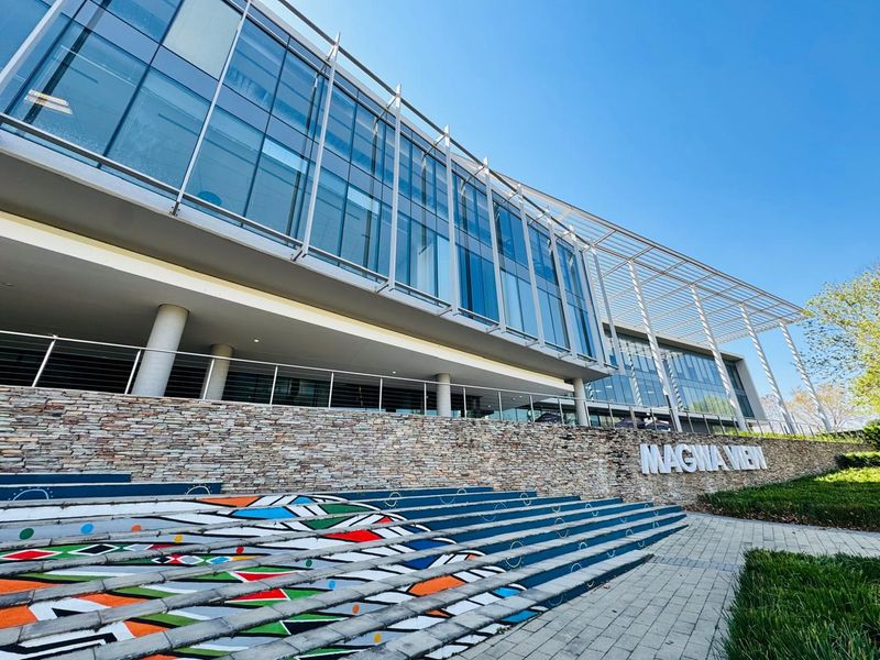 Modern office building exterior featuring a glass facade, stone-clad retaining wall, and decorative concrete stairs at the entrance.
