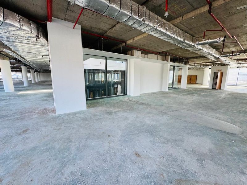 Expansive open-plan office space in shell condition, featuring exposed industrial ceilings, concrete flooring, and glass partitioning, ready for custom fit-out.