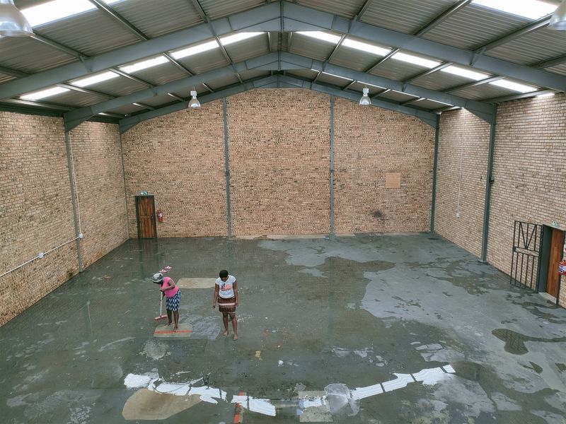 Spacious industrial warehouse unit featuring high ceilings with exposed steel trusses, translucent roof panels for natural light, and durable face brick walls.