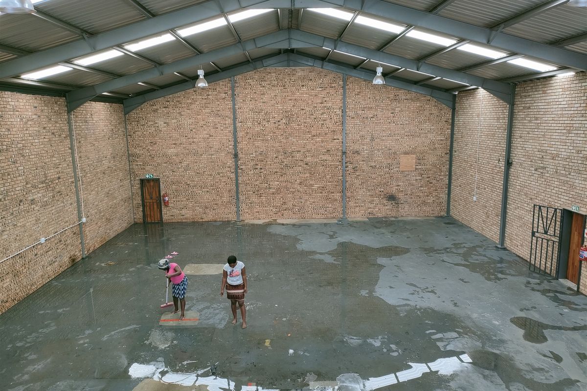 Spacious industrial warehouse unit featuring high ceilings with exposed steel trusses, translucent roof panels for natural light, and durable face brick walls.