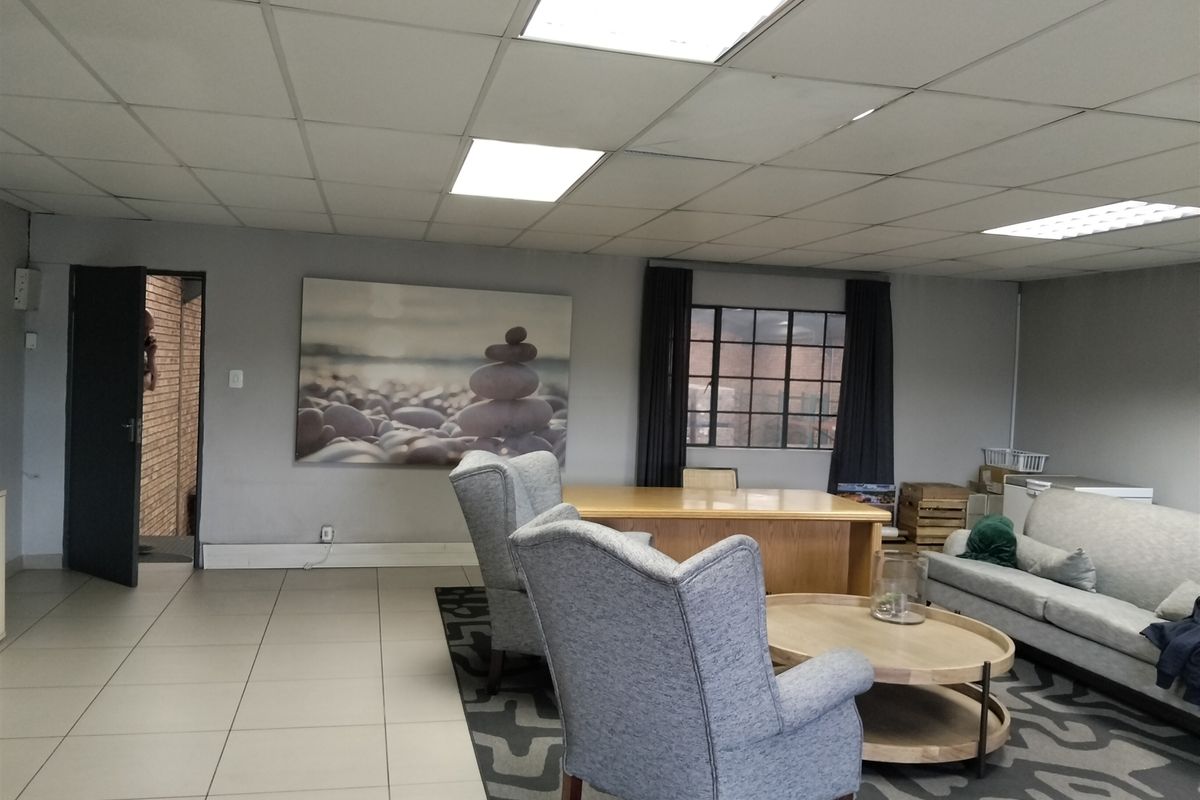 A spacious office or lounge area featuring a suspended ceiling with recessed lighting, tiled flooring, and a large steel-framed window.