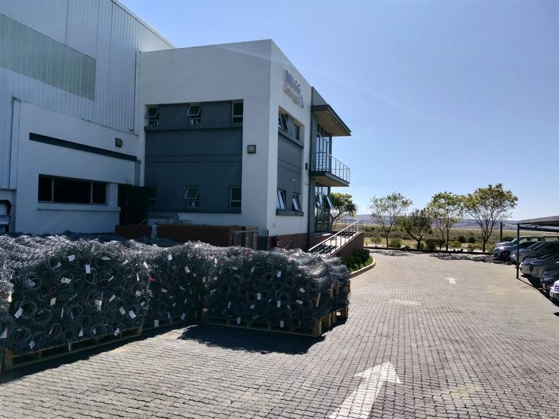 Exterior view of a modern industrial facility featuring a paved driveway, metal cladding, and a balcony entrance.