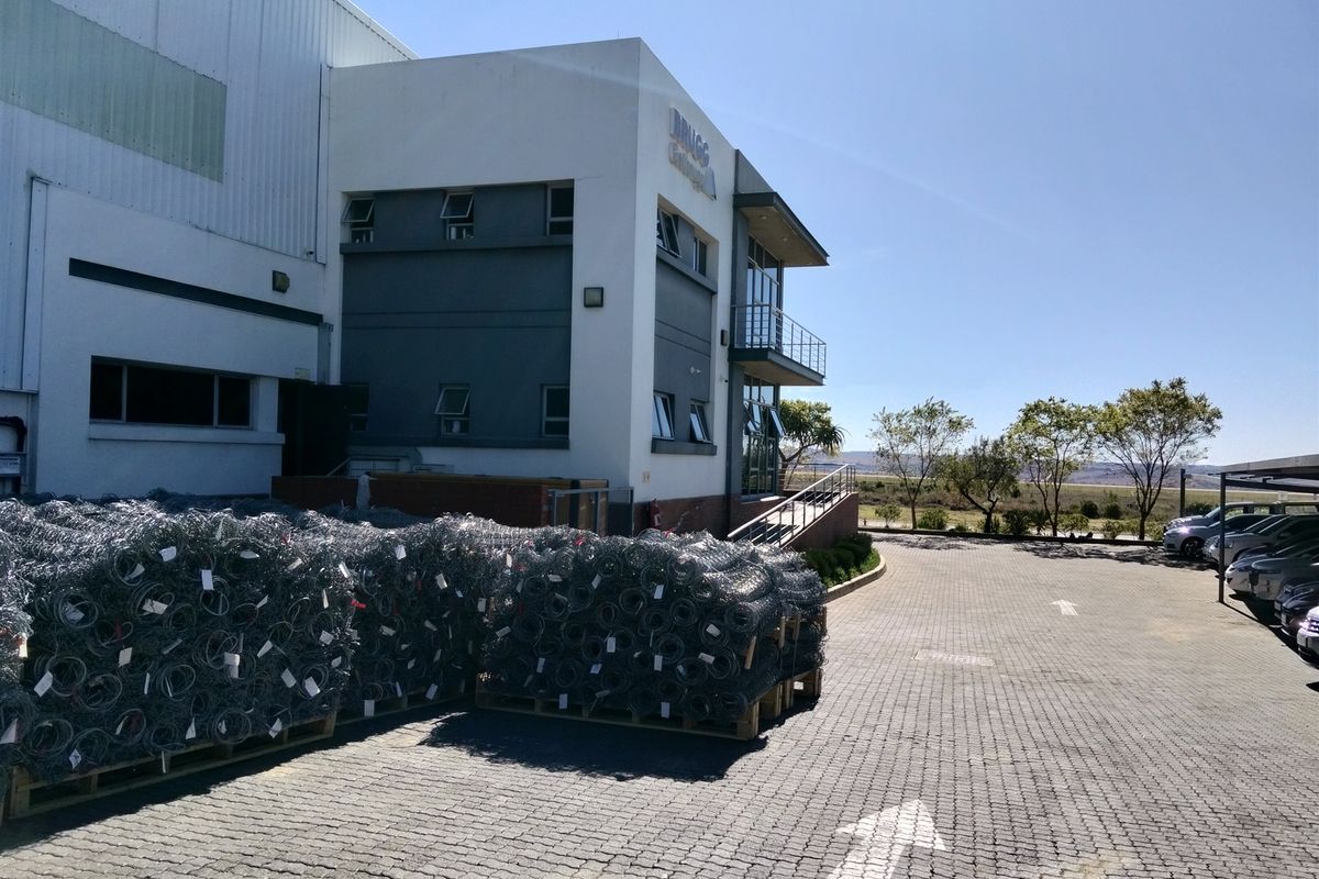 Exterior view of a modern industrial facility featuring a paved driveway, metal cladding, and a balcony entrance.
