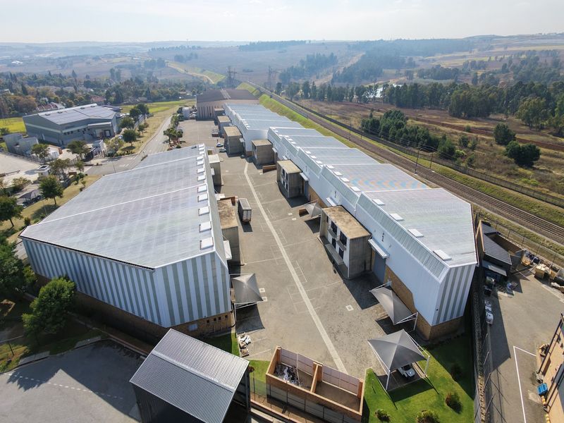 Aerial view of an industrial complex featuring multiple warehouse buildings, extensive paved yard space, and perimeter security fencing.