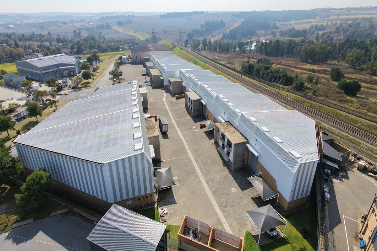 Aerial view of an industrial complex featuring multiple warehouse buildings, extensive paved yard space, and perimeter security fencing.