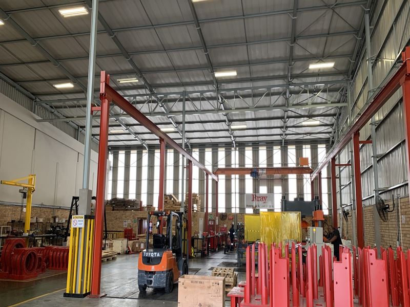 Spacious industrial warehouse facility featuring high ceilings, overhead crane infrastructure, exposed brick walls, and durable concrete flooring suitable for manufacturing or storage operations.