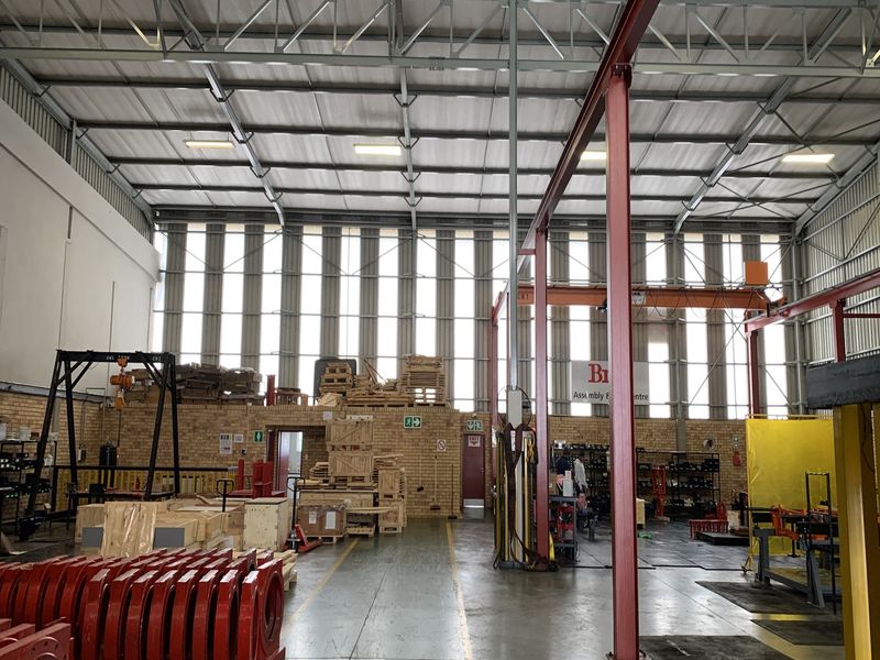 Spacious industrial warehouse featuring a high-clearance steel portal frame, overhead gantry crane, exposed brick walls, and durable concrete flooring suitable for manufacturing or storage.