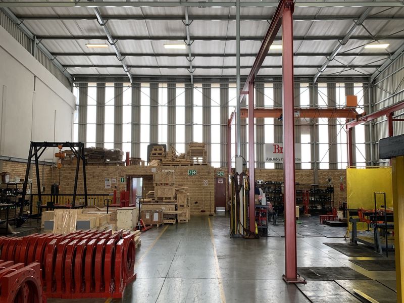 Spacious industrial warehouse facility featuring high ceilings, exposed steel portal frame, overhead gantry crane, and durable concrete flooring suitable for manufacturing or storage operations.