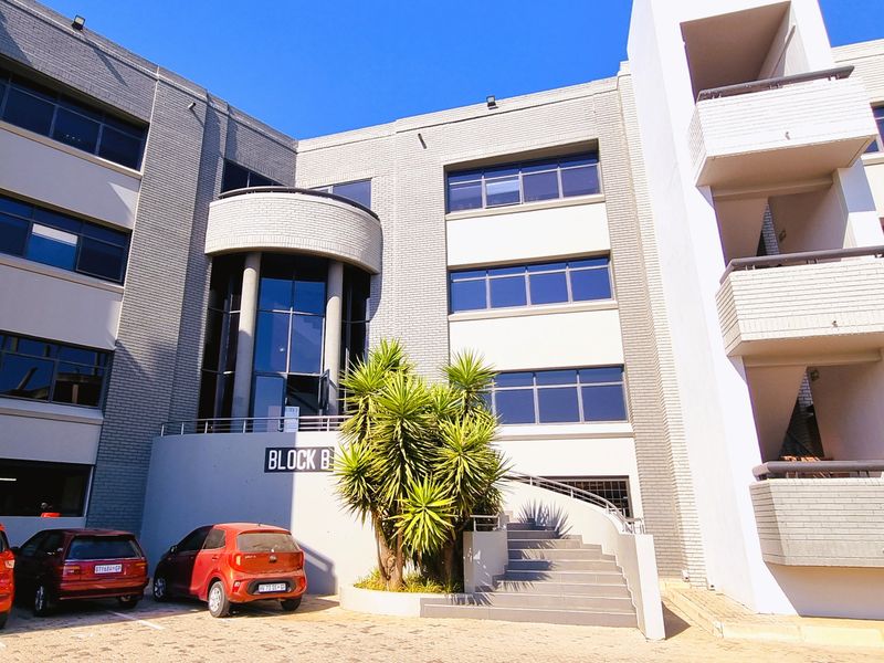 Exterior view of a modern multi-story office building, Block B, featuring brick facade, large windows, and a prominent concrete entrance staircase.