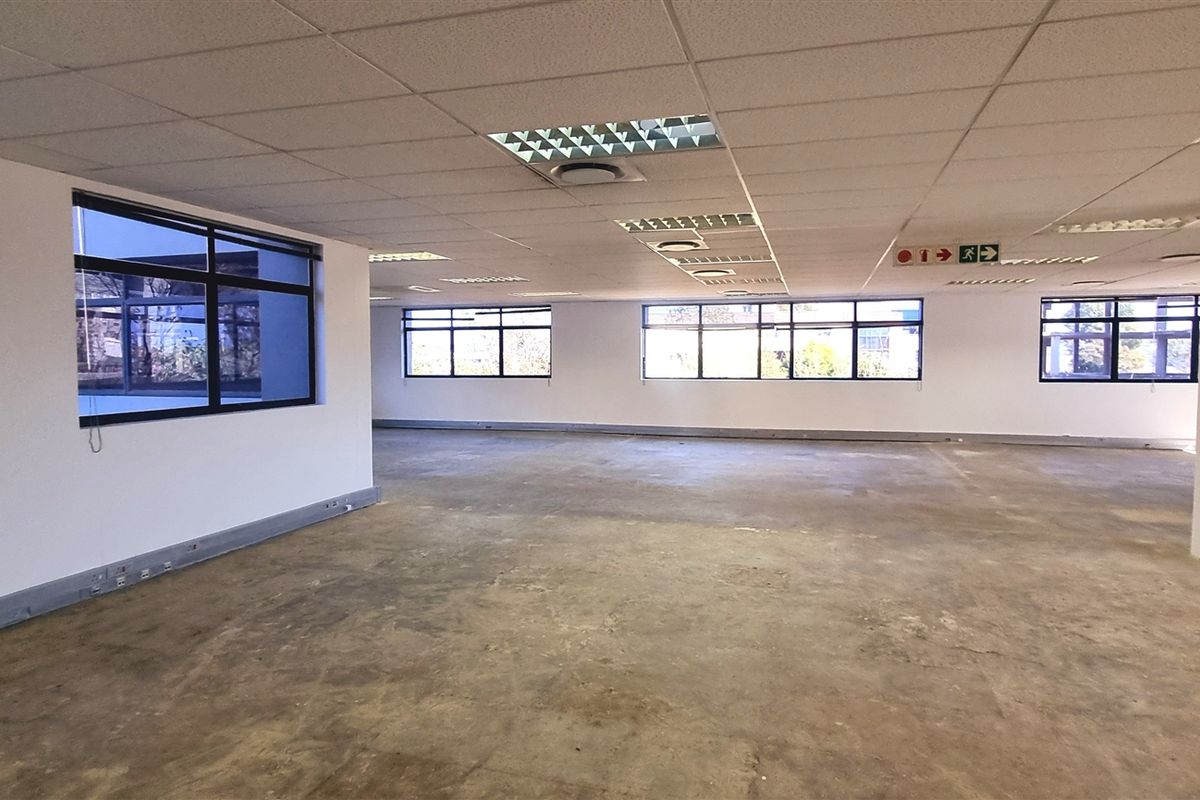 A large, open-plan office space featuring suspended ceilings, recessed lighting, and expansive windows, currently in a shell condition ready for fit-out.